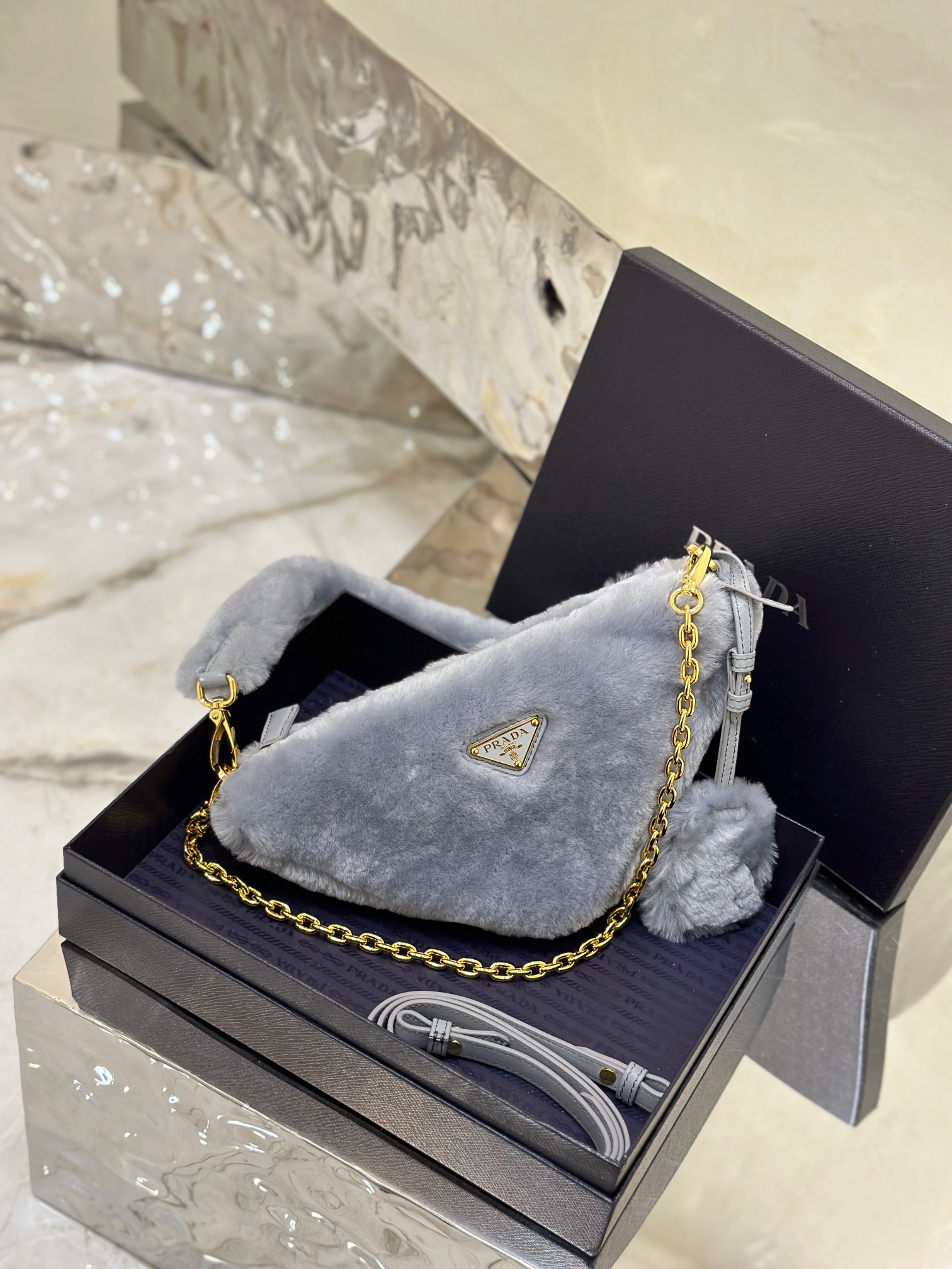 PRADA Shearling Mini Bag. Original Quality Bag including gift box, care book, dust bag, authenticity card. The softness and fuzziness of shearling accentuate the modern, wintry allure of this mini-bag characterized by its harmonious and delicate shape. The bag accented with a chain handle is decorated with the enameled metal triangle logo. | CRIS&COCO Authentic Quality Designer Bags and Luxury Accessories