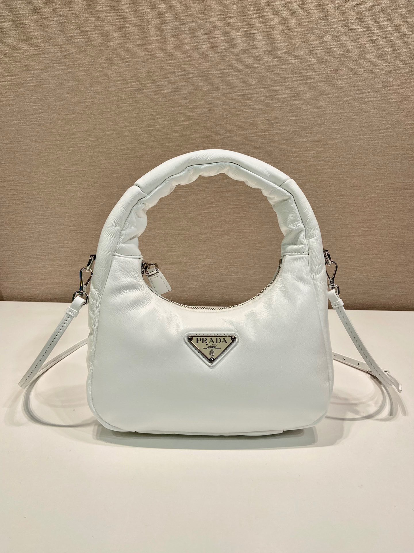 PRADA Soft Padded Mini Bag. Original Quality Bag including gift box, care book, dust bag, authenticity card. A harmonious, bold silhouette characterizes this mini-bag made of padded leather accented with the detachable, adjustable shoulder strap. Defined by its versatile allure, the accessory has a zipper closure and is decorated with the emblematic enameled metal triangle logo. | CRIS&COCO Authentic Quality Designer Bags and Luxury Accessories