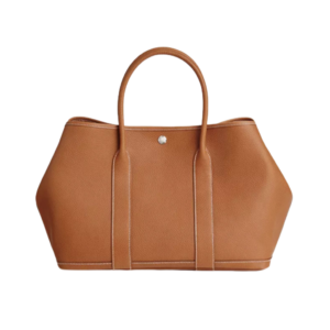 Garden Party: Style for Every Occasion. This Garden Party tote is the perfect blend of style and practicality. This chic and sporty bag is designed for every occasion, whether spending the day amongst the hustle and bustle of the city or enjoying a peaceful weekend in the countryside. Crafted with both leather and canvas, it's the perfect choice for whatever your destination. Not only is it spacious enough to hold your everyday essentials, but it also features Clou de Selle snap closures on the sides for added convenience. This snap that allows the bag to be just the right amount of malleable; to expand and create extra interior space to accommodate larger, or more items at once. Wherever your adventures take you, this exclusive HERMÈS tote will accompany you every step of the way. | CRIS&COCO Authentic Quality Designer Bags and Luxury Accessories