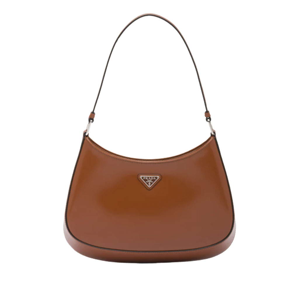 PRADA-Cleo-Shoulder-Bag The PRADA Galleria Bag in black leather, spotlighted on a minimalist white shelf in a luxury boutique.