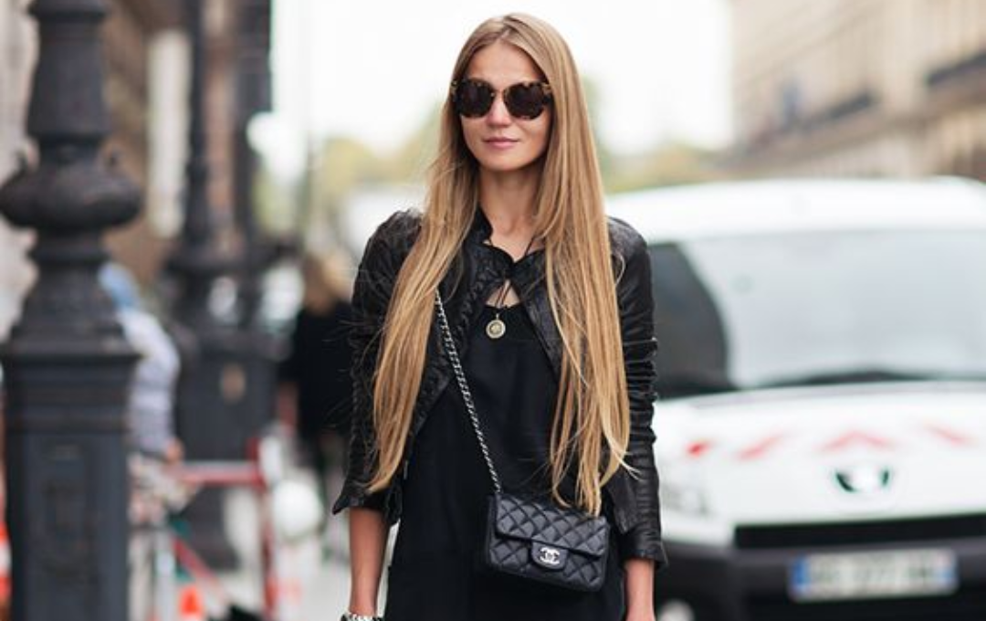 Home 6 Classy woman wearing black, holding a black Chanel Flap Bag.