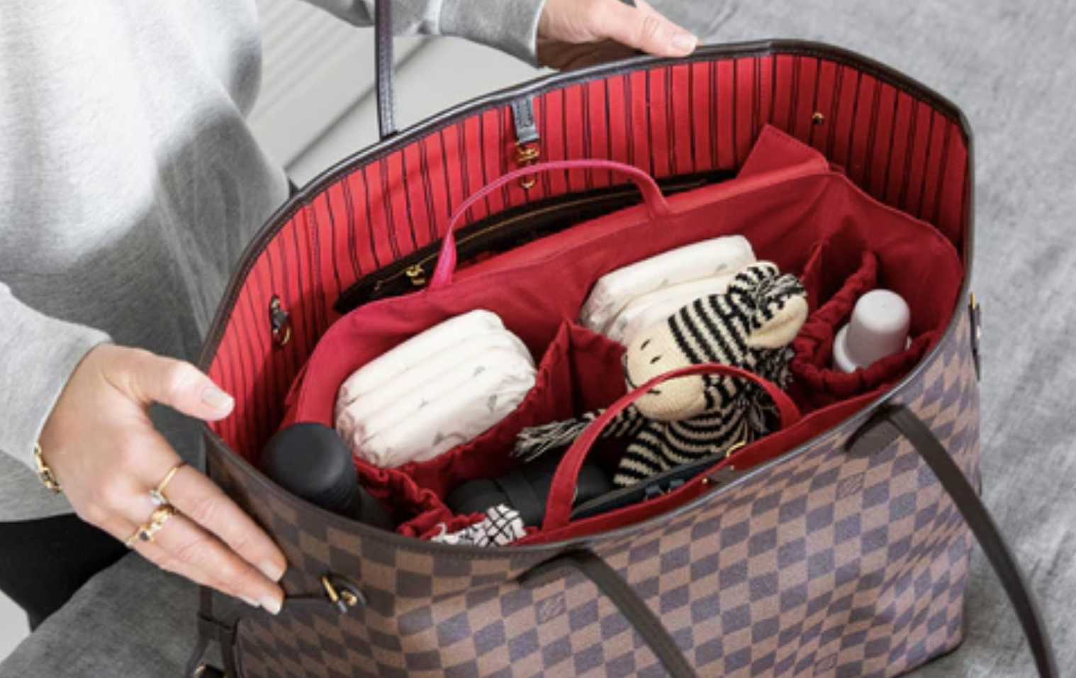 A LOUIS VUITTON Neverfull, overflowing with everyday essentials. LOUIS VUITTON Neverfull tote bag with essentials spilling out.