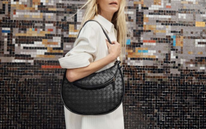 Effortless Elegance: BOTTEGA VENETA in Action - CRIS&COCO A model elegantly holding a BOTTEGA VENETA bag in a modern urban setting.