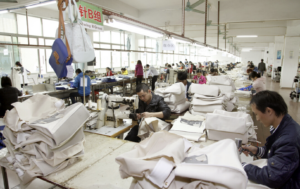 Factory workers assembling luxury handbags in a large warehouse