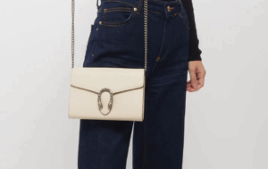 A crisp white GUCCI Wallet With Chain placed on a glossy marble table.