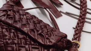 A craftsman mid-stitch, transforming leather into a bag that looks like it flew first class from Paris — but didn’t.