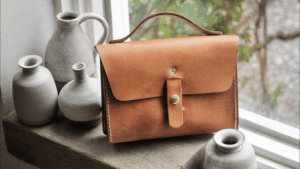 Leather bag workshop with artisan hands at work on premium materials