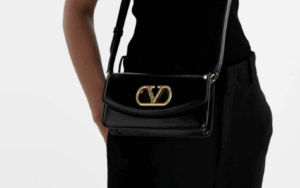 VALENTINO leather clutch replica with bold gold V logo resting on mirrored vanity