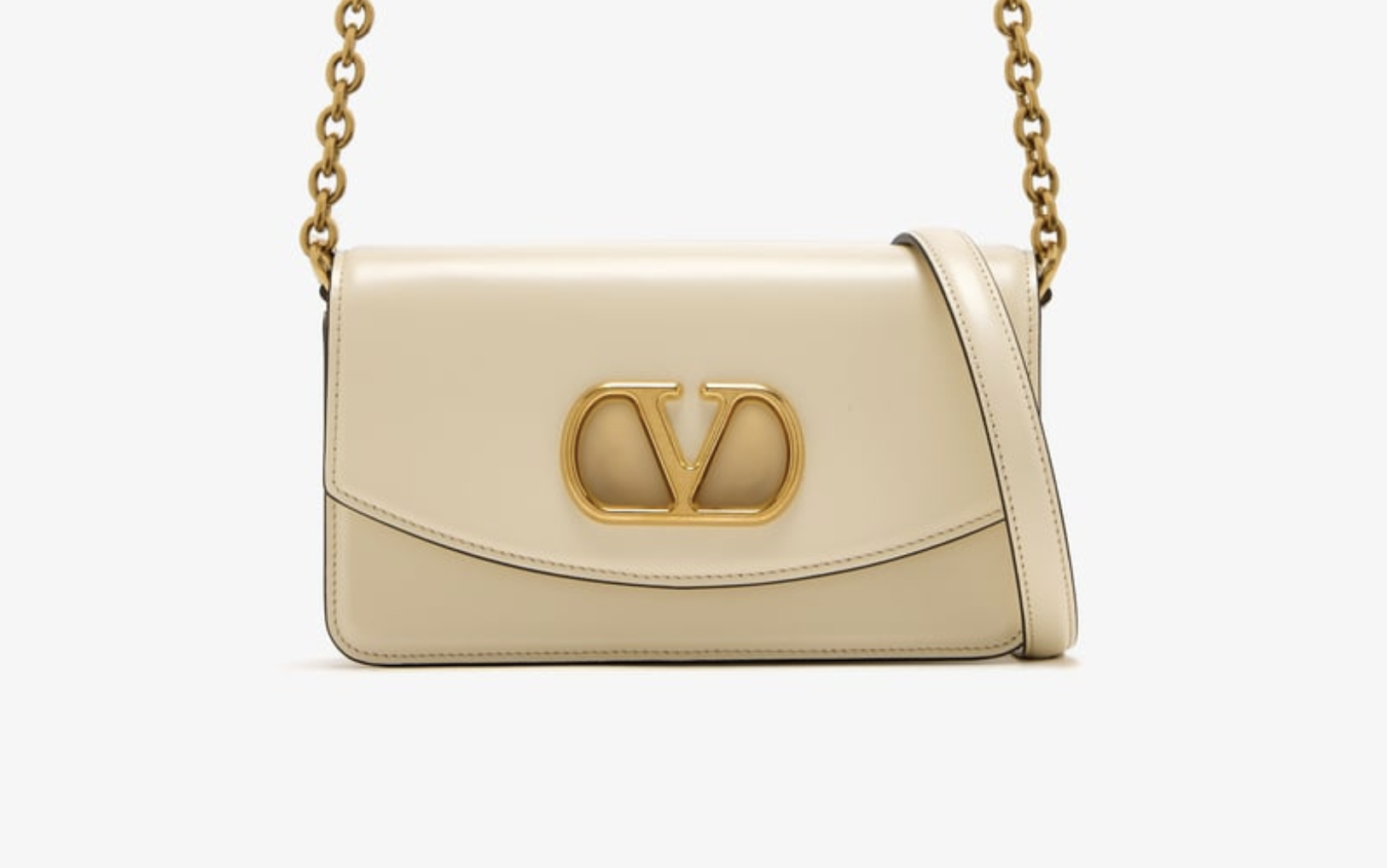 Close-up of gold V logo on VALENTINO replica clutch in studio lighting Close-up of gold V logo on VALENTINO replica clutch in studio lighting