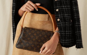 Graduate posing with a luxury designer handbag on a university lawn