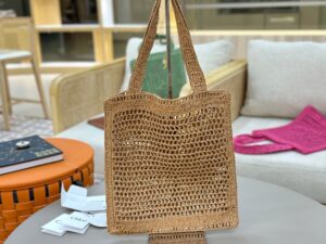 Summer Banana Tote Bag. Authentic quality luxury bag crafted in genuine leather comes with authenticity card, dust bag and gift bag. Heritage in Hand: Where Artisan Craft Meets Summer Elegance. Introducing the Summer Banana Tote—an artisanal masterpiece crafted from raffia and calfskin by a single artisan over 4.5 days in partnership with Made For A Woman. This spacious tote is adorned with a handwritten signature inspired by *loé’s rich heritage, while a playful dangling chain and delicate charms add the perfect finishing touch. A celebration of craftsmanship and effortless summer style.