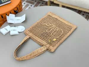 Summer Banana Tote Bag. Authentic quality luxury bag crafted in genuine leather comes with authenticity card, dust bag and gift bag. Heritage in Hand: Where Artisan Craft Meets Summer Elegance. Introducing the Summer Banana Tote—an artisanal masterpiece crafted from raffia and calfskin by a single artisan over 4.5 days in partnership with Made For A Woman. This spacious tote is adorned with a handwritten signature inspired by *loé’s rich heritage, while a playful dangling chain and delicate charms add the perfect finishing touch. A celebration of craftsmanship and effortless summer style.