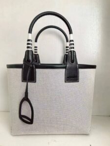 Steeple 25 Bag. Authentic quality luxury bag crafted in genuine leather comes with authenticity card, dust bag and gift bag. Where art meets heritage. The *rmès Steeple Bag is a charming fusion of heritage and artistry, crafted from a blend of canvas and Swift leather. Its design pays tribute to *rmès’ equestrian roots with whip-shaped handles and a stirrup-inspired charm, adding a playful yet sophisticated touch. Lightweight yet spacious, the Steeple is ideal for daily use. Whether you opt for a vibrant motif or a sleek, single-color design, this bag stands out as an artistic expression of luxury that seamlessly integrates into a modern lifestyle. Praised for its unique aesthetic and accessibility within the *rmès lineup, the Steeple Bag is adored by fashion enthusiasts who appreciate its colorful palette and bold personality. While it’s best suited for those who enjoy the texture and look of canvas, it remains a versatile statement piece that captures the spirit of everyday elegance.