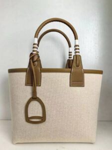 Steeple 25 Bag. Authentic quality luxury bag crafted in genuine leather comes with authenticity card, dust bag and gift bag. Where art meets heritage. The *rmès Steeple Bag is a charming fusion of heritage and artistry, crafted from a blend of canvas and Swift leather. Its design pays tribute to *rmès’ equestrian roots with whip-shaped handles and a stirrup-inspired charm, adding a playful yet sophisticated touch. Lightweight yet spacious, the Steeple is ideal for daily use. Whether you opt for a vibrant motif or a sleek, single-color design, this bag stands out as an artistic expression of luxury that seamlessly integrates into a modern lifestyle. Praised for its unique aesthetic and accessibility within the *rmès lineup, the Steeple Bag is adored by fashion enthusiasts who appreciate its colorful palette and bold personality. While it’s best suited for those who enjoy the texture and look of canvas, it remains a versatile statement piece that captures the spirit of everyday elegance.