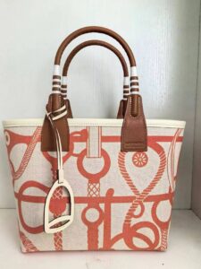 Steeple 25 Bag. Authentic quality luxury bag crafted in genuine leather comes with authenticity card, dust bag and gift bag. Where art meets heritage. The *rmès Steeple Bag is a charming fusion of heritage and artistry, crafted from a blend of canvas and Swift leather. Its design pays tribute to *rmès’ equestrian roots with whip-shaped handles and a stirrup-inspired charm, adding a playful yet sophisticated touch. Lightweight yet spacious, the Steeple is ideal for daily use. Whether you opt for a vibrant motif or a sleek, single-color design, this bag stands out as an artistic expression of luxury that seamlessly integrates into a modern lifestyle. Praised for its unique aesthetic and accessibility within the *rmès lineup, the Steeple Bag is adored by fashion enthusiasts who appreciate its colorful palette and bold personality. While it’s best suited for those who enjoy the texture and look of canvas, it remains a versatile statement piece that captures the spirit of everyday elegance.