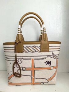 Steeple 25 Bag. Authentic quality luxury bag crafted in genuine leather comes with authenticity card, dust bag and gift bag. Where art meets heritage. The *rmès Steeple Bag is a charming fusion of heritage and artistry, crafted from a blend of canvas and Swift leather. Its design pays tribute to *rmès’ equestrian roots with whip-shaped handles and a stirrup-inspired charm, adding a playful yet sophisticated touch. Lightweight yet spacious, the Steeple is ideal for daily use. Whether you opt for a vibrant motif or a sleek, single-color design, this bag stands out as an artistic expression of luxury that seamlessly integrates into a modern lifestyle. Praised for its unique aesthetic and accessibility within the *rmès lineup, the Steeple Bag is adored by fashion enthusiasts who appreciate its colorful palette and bold personality. While it’s best suited for those who enjoy the texture and look of canvas, it remains a versatile statement piece that captures the spirit of everyday elegance.