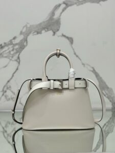 Buckle Small Leather Handbag. Authentic quality luxury bag crafted in genuine leather comes with authenticity card, dust bag and gift bag. Sophistication Meets Utility. Sleek, structured, and undeniably Pr*da — the Buckle Small Leather Handbag captures the brand’s signature balance of minimalist elegance and refined detail. Crafted in smooth leather with a buttery-soft nappa interior, this compact piece is a masterclass in functional luxury. A standout feature? Its interchangeable belt strap, adding a bold, modern twist to the timeless silhouette. Whether you're heading to a meeting or a soirée, this bag adapts seamlessly to your mood and moment. Finished with the embossed iconic logo, it’s a quiet statement of taste and distinction. A versatile companion for the woman who appreciates precision, polish, and just the right touch of edge.