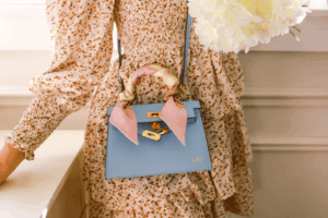 Mini pink replica KELLY bag on marble café table with coffee and Vogue magazine