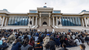Protesters in Ulaanbaatar holding up signs featuring luxury bags alongside slogans demanding government accountability