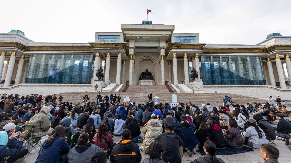 Protesters in Ulaanbaatar holding up signs featuring luxury bags alongside slogans demanding government accountability Protesters in Ulaanbaatar holding up signs featuring luxury bags alongside slogans demanding government accountability