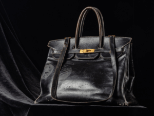 Woman holding a vintage HERMÈS Birkin in a crowded urban street