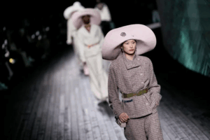 Maximalist hats and structured tailoring take center stage on the runway, turning classic silhouettes into high drama.