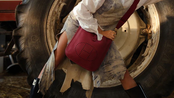 A rustic chic look with a red leather bag and a striking backdrop of a tractor tire. A rustic chic look with a red leather bag and a striking backdrop of a tractor tire.