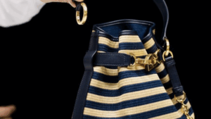 Close-up of a Dior C’est Bag in striped raffia and leather with gold accents, showcasing craftsmanship and texture.