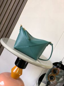 Puzzle Fold Pouch. Authentic quality luxury bag crafted in genuine leather comes with authenticity card, dust bag and gift bag. Sculpted Sophistication — The Art of Function. The Puzzle Fold Pouch redefines modern elegance with its sculptural geometry and effortless versatility. Crafted in luxurious shiny nappa calfskin, its signature folded panels create a dynamic, architectural silhouette that’s instantly recognizable. Both stylish and practical, this pouch transitions seamlessly from day to night—perfect for carrying essentials with a touch of *OEWE sophistication. A masterpiece of craftsmanship, it’s the ultimate blend of innovation and timeless design.